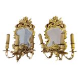 A PAIR OF EARLY 20TH CENTURY BRASS GIRONDELLE MIRRORS cast with cherubs and facial masks above