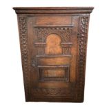 A 17TH CENTURY CARVED OAK WALL HANGING CABINET With arched and rectangular panelled single door