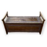 AN AFRICAN HARDWOOD SETTLE With open ends, centred with a rise and fall top above carved fielded