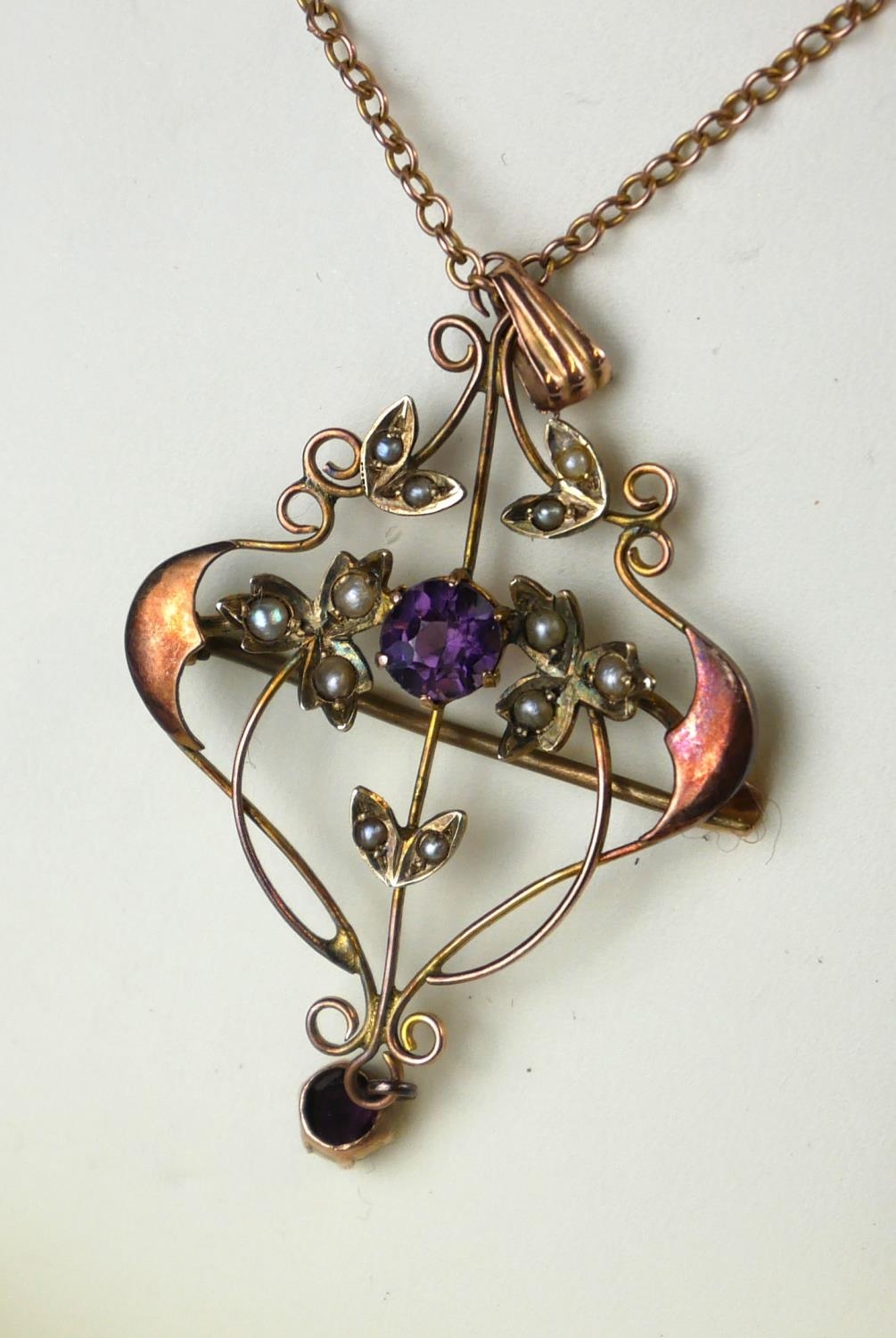 AN ART NOUVEAU 9CT GOLD, AMETHYST AND SEED PEARL PENDANT NECKLACE A central round cut amethyst in