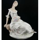 LLADRO, A LARGE PORCELAIN FIGURE OF A YOUNG LADY IN A LONG DRESS Seated on a rock holding a fan,