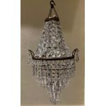 AN EDWARDIAN GILT METAL AND CRYSTAL HUNG THREE TIER CHANDELIER. (52cm)