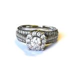 A 14ct WHITE GOLD AND DIAMOND CLUSTER RING Having a central round cut diamond, edged with diamonds