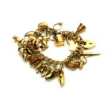 A VINTAGE 9CT GOLD CHARM BRACELET Having pierced wire links and a heart form clasp, set with various