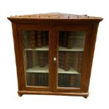 A VICTORIAN PITCH PINE FLOOR STANDING CORNER CABINET With two glazed doors enclosing shelves. (