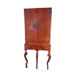 A QUEEN ANNE STYLE WALNUT DRINKS CABINET With two doors and enclosing a fitted interior above a