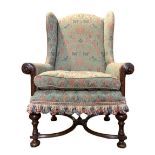 AN EARLY 18TH CENTURY WALNUT WING ARMCHAIR In a green floral fabric upholstery, with scroll show