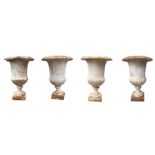 A SET OF FOUR EARLY 20TH CENTURY FRENCH CAST IRON CAMPANA FORM URNS With melon section bodies raised
