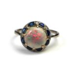 AN ART DECO 18CT WHITE GOLD, OPAL, SAPPHIRE AND DIAMOND RING Having a cabochon cut opal edged with