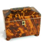 AN ANTIQUE TORTOISESHELL TEA CADDY Having a sarcophagus top, the interior lid concealing two