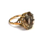 A VINTAGE 9CT GOLD AND SMOKY QUARTZ RING The faceted round cut stone on a plain gold shank. (