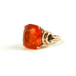 AN ART DECO YELLOW METAL AND FIRE OPAL RING The cushion cut central stone flanked by geometric