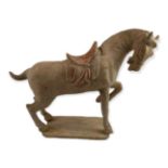 A TANG STYLE POTTERY FIGURE OF A PRANCING HORSE. (h 33cm x length 41cm)