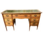A LATE VICTORIAN OAK DESK Having a tooled leather top and central drawer flanked by two banks of