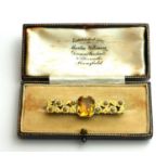 AN ART DECO WHITE METAL AND ENAMEL CITRINE BROOCH The central cushion cut diamond with cream