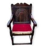 A 17TH CENTURY OAK WAINSCOT CHAIR The shaped top above an arched carved panel back, on turned legs