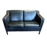 A MID CENTURY BLACK LEATHER UPHOLSTERED TWO SEAT SETTEE Complete with loose cushions, on tapering