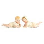 A PAIR OF 20TH CENTURY AMUSING BISQUE PIANO DOLLS Both in Victorian dress and painted in pastel