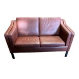 A MID CENTURY TAN LEATHER UPHOLSTERED TWO SEAT SETTEE Complete with loose cushions, on tapering