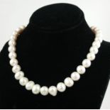 A STRING OF WHITE FRESHWATER CULTURED PEARLS with a 9ct rose gold ball clasp. 18 inches.