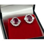 A PAIR OF 18CT WHITE GOLD OVAL RUBY AND DIAMOND CLUSTER STUDS. (Rubies 2.96ct, Diamonds 1.00ct)