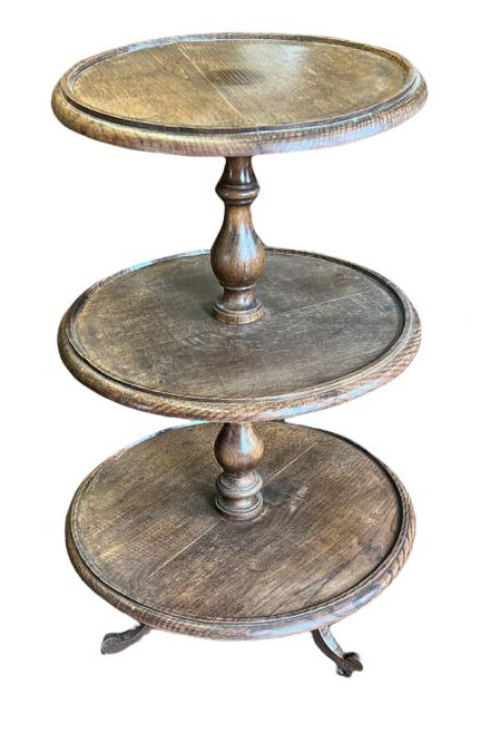 A VICTORIAN OAK THREE GRADUATED TIER DUMBWAITER With dish tops on turned column supports, standing