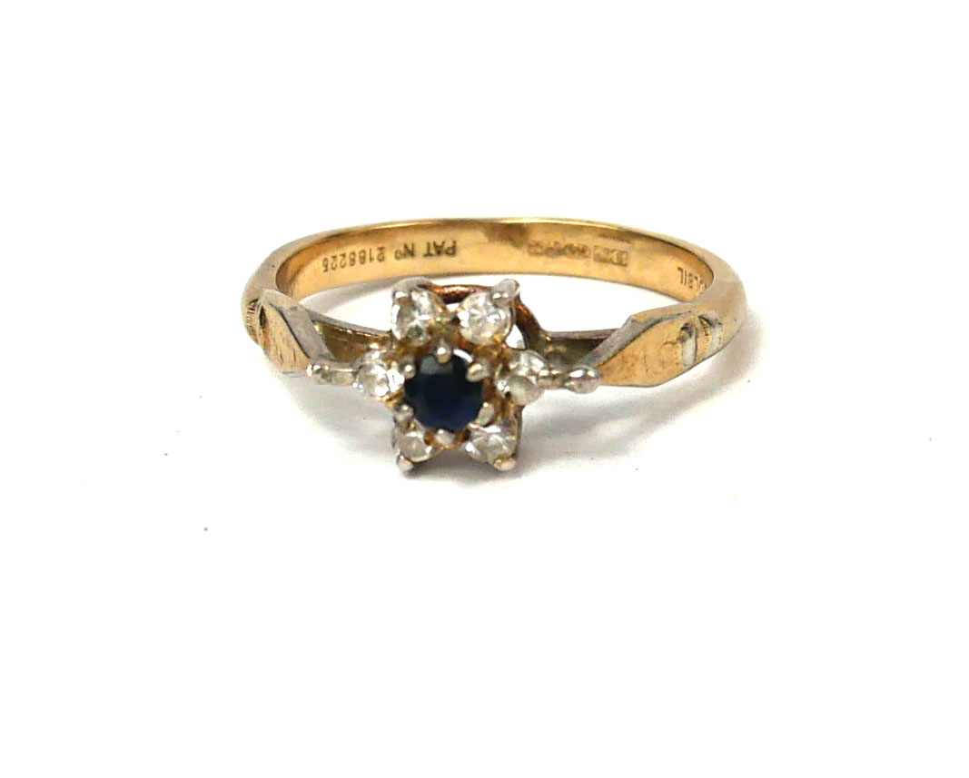 A 9CT GOLD, SAPPHIRE AND DIAMOND FLORAL SET IN A SILVER MOUNT. (size L\M) Condition: good