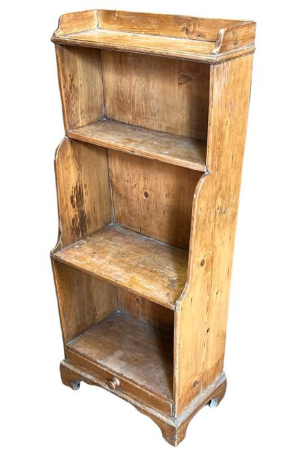 AN EDWARDIAN PINE WATERFALL BOOKCASE The open shelves above a single drawer, raised on bracket feet.