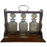 A GOOD LATE VICTORIAN OAK CASED TANTALUS Containing three hobnail crystal cut glass decanters,