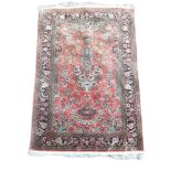 A FINE PERSIAN QUM SILK RUG The central field woven with birds and vase of flowers contained in five