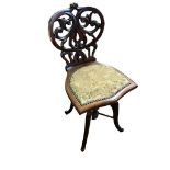 A LATE VICTORIAN MAHOGANY MUSIC CHAIR Having a carved and pierced heart form back and upholstered