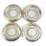 A SET OF FOUR SILVER AND CUT GLASS CIRCULAR ASHTRAYS Bases with star cut designs, along with a set