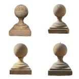 A SET OF FOUR RECONSTITUTED STONE GATE POST FINIALS With spheres seated on socle and platform bases.