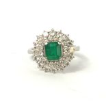 A VINTAGE PLATINUM, EMERALD AND DIAMOND CLUSTER RING The single baguette cut emerald edged with