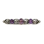 AN EARLY 20TH CENTURY WHITE METAL, AMETHYST AND DIAMOND BROOCH Three graduated oval cut amethysts