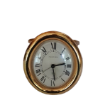 CARTIER, BAIGNOIRE, A GILT METAL OVAL TRAVELLING CLOCK On a strut support, quartz movement. (10cm