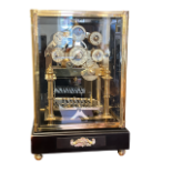 A GLASS CASED BRASS MOONPHASE ROLLING BALL CLOCK With enamel cabochons, days and dates, above a