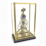 A BRASS SKELETON CLOCK WITH ENAMELED MOONPHASE AND DATE IN A GLASS CASE Eagle crest, 8 day movement,