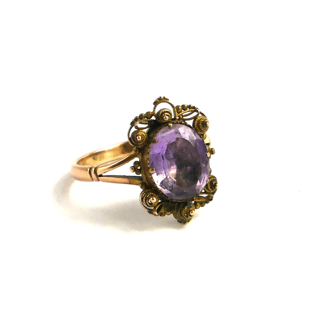 AN EARLY 20TH CENTURY YELLOW METAL AND AMETHYST RING The central oval cut stone set in a filigree