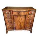 A GEORGIAN MAHOGANY SERPENTINE FRONTED KNEEHOLE DESK With an arrangement of seven drawers fitted