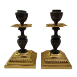 A PAIR OF MID 19TH CENTURY GILT BRASS CHAMBER CANDLESTICKS Raised on square stepped bases, the