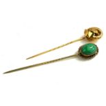 TWO EARLY 20TH CENTURY YELLOW METAL STICK PINS A pin set with cabochon cut green hardstone and the