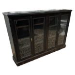 AN EDWARDIAN MAHOGANY FLOOR STANDING BOOKCASE With four glaze doors enclosing adjustable shelves,