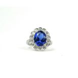 AN 18CT WHITE GOLD OVAL TANZANITE AND DIAMOND CLUSTER RING. (Approx Tanzanite 4.55ct, Diamonds 1.