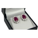A PAIR 18CT WHITE GOLD LARGE OVAL RUBY AND DIAMOND CLUSTER STUDS, boxed. (Apporx Rubies 3.56ct