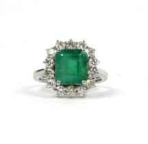 A 18CT WHITE GOLD EMERALD AND DIAMOND CLUSTER RING. (Approx Emerald 3.68ct, Diamonds 1.05ct)