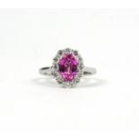 AN 18CT WHITE GOLD OVAL PINK SAPPHIRE AND DIAMOND CLUSTER RING. (Approx pink sapphire 2.15ct,