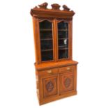 AN EDWARDIAN CARVED WALNUT GLAZED BOOKCASE Above two single drawers, two panel drawers, raised on