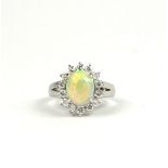 A PLATINUM CABOCHON OVAL OPAL RING with a halo of round brilliant cut diamonds. (Approx Opal 1.05ct,