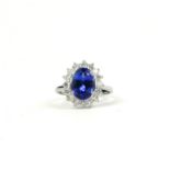 AN 18CT WHITE GOLD RING SET WITH AN OVAL TANZANITE SURROUNDED BY A HALO OF ROUND BRILLIANT CUT